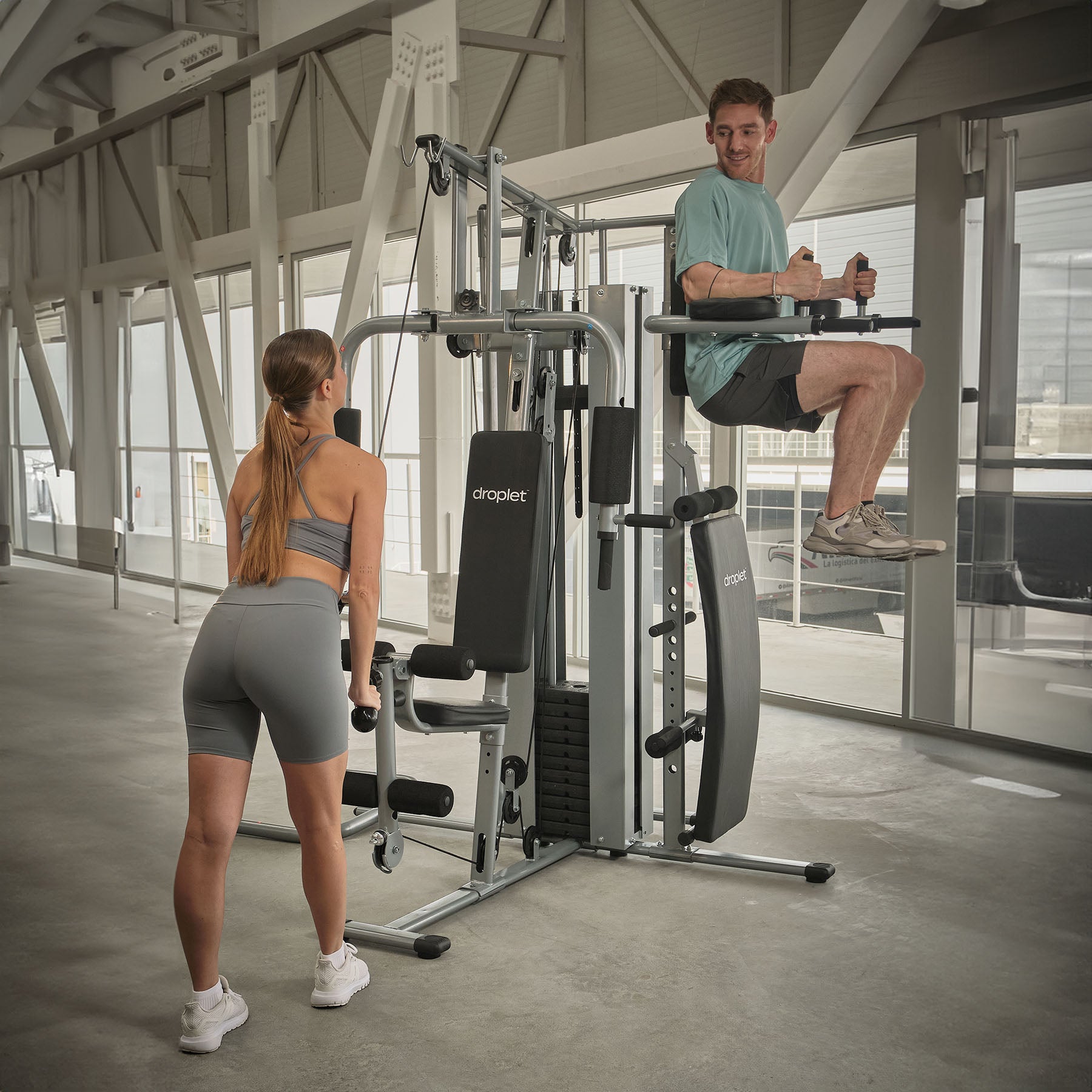 Imagen ambientada de gym en casa con dos personas usando estaciones distintas.